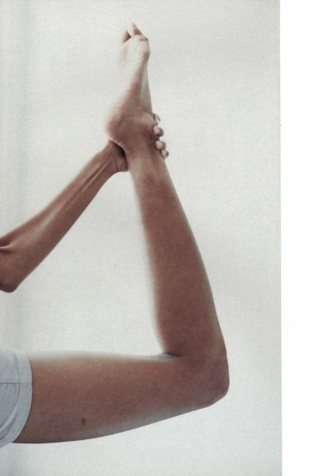 A hand holding a foot overhead in a deep stretch